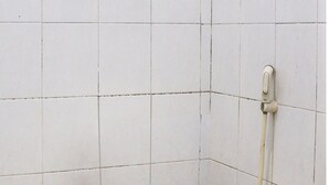 A small, basic bathroom with a toilet, a wall-mounted faucet, and a tiled floor. - Hotel O Wisma Harapan Baik (Kupang)