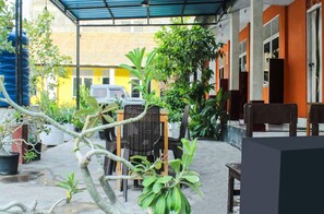 Un'area patio esterna con zona salotto coperta, piante in vaso e un veicolo parcheggiato.