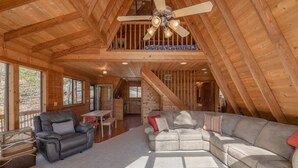 Un vaste espace de vie de style loft, doté d’un grand ventilateur de plafond, d’un canapé d’angle, d’un fauteuil en cuir et d’un coin repas.