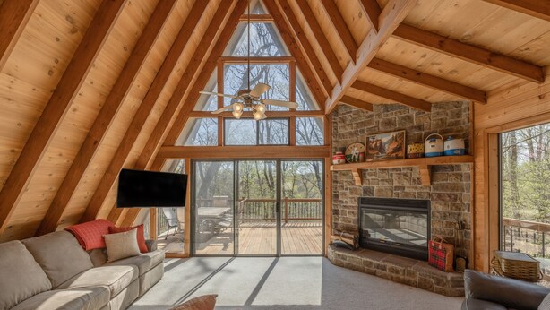 Une pièce chaleureuse de style loft, dotée d’une cheminée en pierre, de poutres en bois et d’une grande porte-fenêtre coulissante donnant sur une terrasse extérieure.