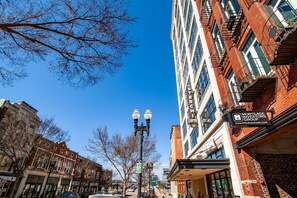 A multi-story building with a sign for 'Mortgage Investors Group' and a street view with trees and parked cars. - Historic Downtown Loft with Modern Flare (Knoxville)