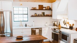 Een moderne keuken met houten plafond, roestvrijstalen apparatuur en witte kasten.