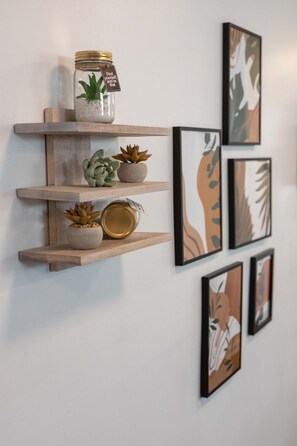 A wall with multiple shelves displaying potted plants and framed artwork. - Close To Music Row Touchless 4bd Unit (Nashville)