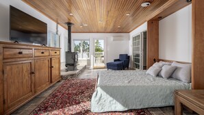 A spacious bedroom with a large bed, a wooden ceiling, a TV, and a fireplace. - 8 Lighthouse Way - Beautiful home with a private elevator! (Lewes)