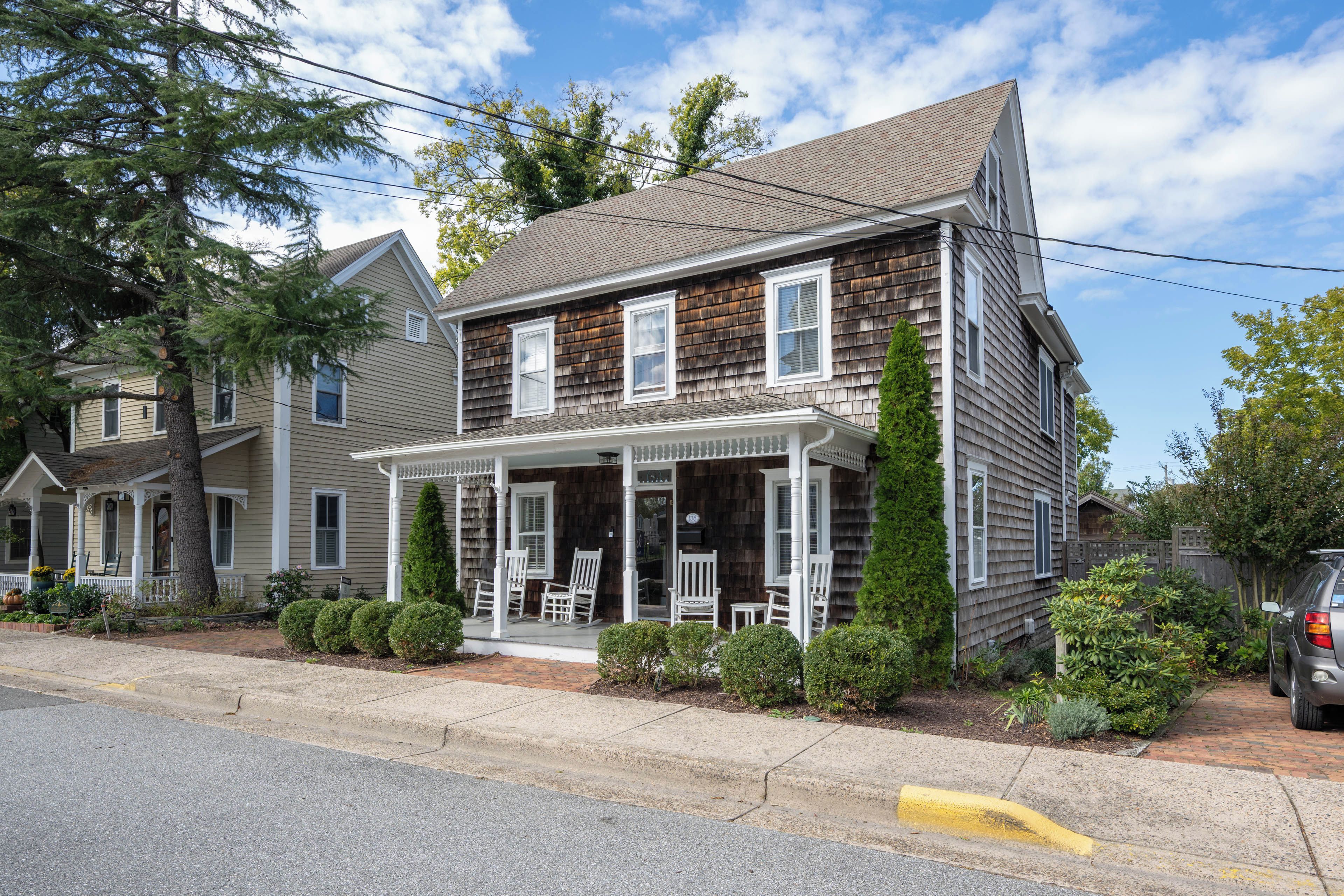 A two-story house with a porch, a chimney, and a small garden.