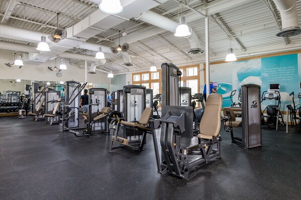 A gym with various exercise machines, large windows, and a motivational quote on the wall. - Newly built end unit townhouse with Pond views in The Peninsula! (Millsboro)