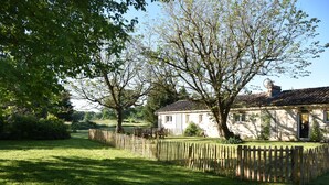 Ein Haus mit umzäunter Garten, Holzfence und einem Baum im Vordergrund.