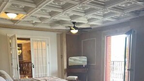 A bedroom with a bed, a nightstand, a ceiling fan, a large window, and a view of the outside. - Two master suites in historic downtown (Luray)