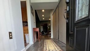 A hallway with a wooden floor, a black door, and a small table with chairs. - Two master suites in historic downtown (Luray)