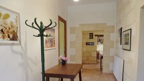 A hallway with a wooden table and a green coat stand, a framed picture on the wall, and a radiator on the right. - Gite DE LA Lande ST Jean (SAINT-LOUBES)