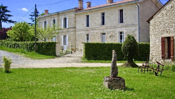 A stone building with a tiled roof, a gravel driveway, and a well-maintained lawn. - Gite DE LA Lande ST Jean (SAINT-LOUBES)