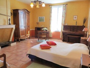 Een slaapkamer met een bed, houten meubels, een piano en een raam met gordijnen.