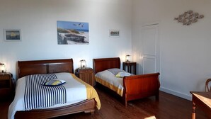 A bedroom with two wooden beds, a white door, and wall art including a seagull and a boat. - Gite DE LA Lande ST Jean (SAINT-LOUBES)