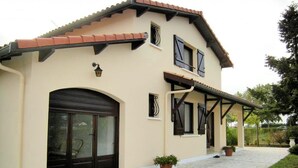 Una casa a due piani con tetto in tegole, un'ampia porta garage e un portico coperto.