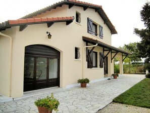 A two-story house with a tiled roof, a large garage door, and a covered porch area. - Gite LE Logis DE LA Perichere (CASTRES-GIRONDE)