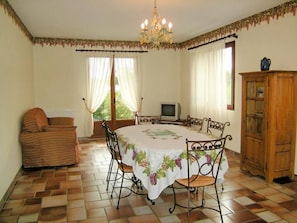 A dining area with a round table, chairs, a television, and a cabinet. - Gite LE Logis DE LA Perichere (CASTRES-GIRONDE)
