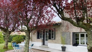 Une maison avec un patio, un espace salon extérieur et un jardin.