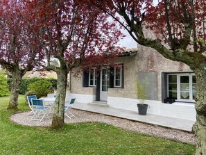 A house with a patio, outdoor seating, and a garden.