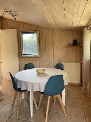 Een kamer met houten lambrisering, een ronde tafel, twee stoelen, een raam en een radiator.