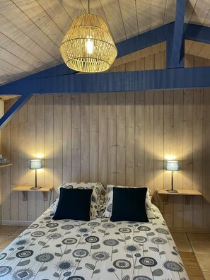 Een slaapkamer met een bed, twee bedlampen, een hanglamp en houten lambrisering.