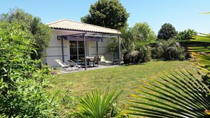 A house with a covered patio, outdoor furniture, and a well-maintained lawn.