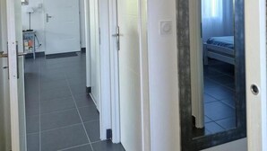 A hallway with a door leading to a room with a bed. - Aux Lauriers Roses - Hourtin (HOURTIN)