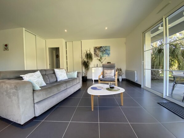 A modern living room with a grey sofa, a coffee table, and a chair with a cushion.