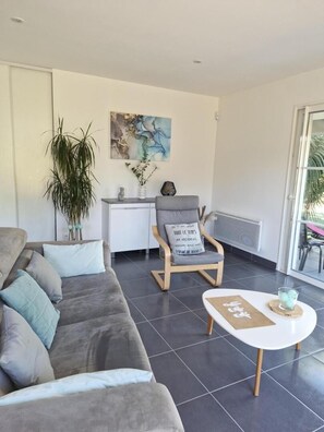 A modern living room with a grey sofa, a white coffee table, and a wooden chair.