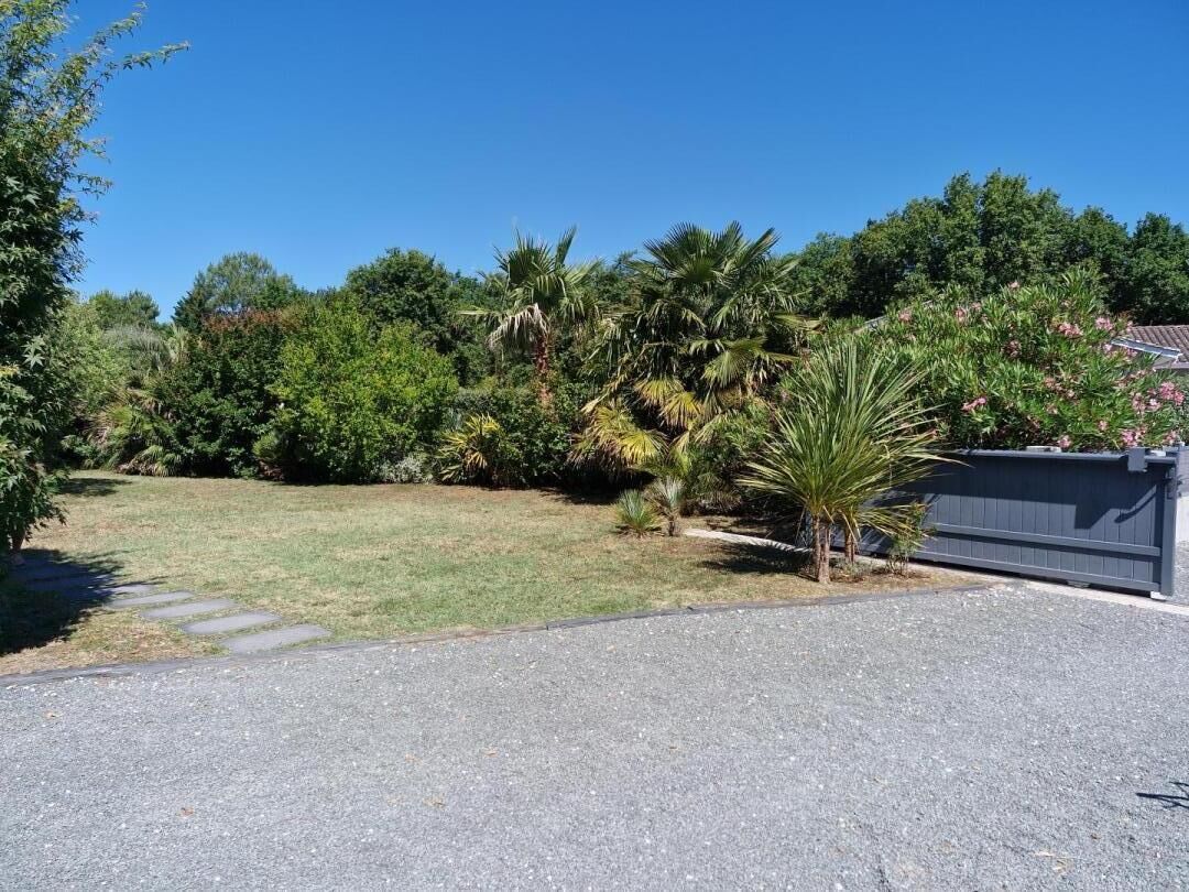 A paved driveway leading to a house with a fenced backyard.