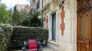 An outdoor seating area with a table and chairs, a hedge, and a building facade with a door labeled 'Dacha'.