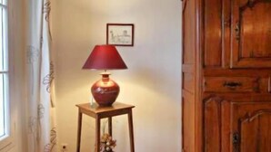 Una habitación con un armario de madera, una mesita con una lámpara y una ventana con cortinas.