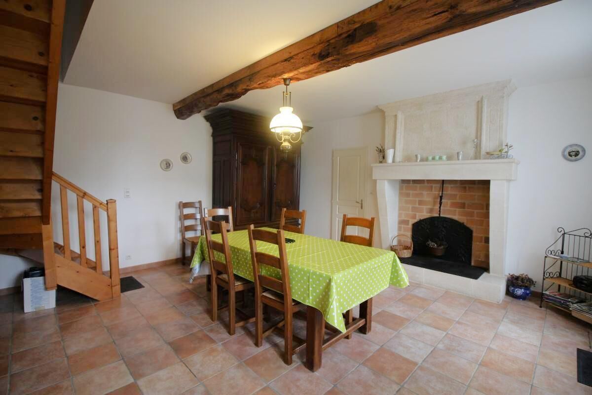 A dining area with a table set for four, wooden chairs, a fireplace, and a staircase.