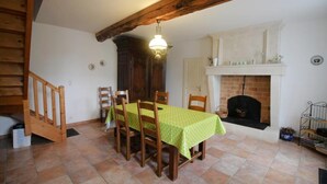 Un comedor con una mesa dispuesta para cuatro personas, sillas de madera, una chimenea y una escalera.