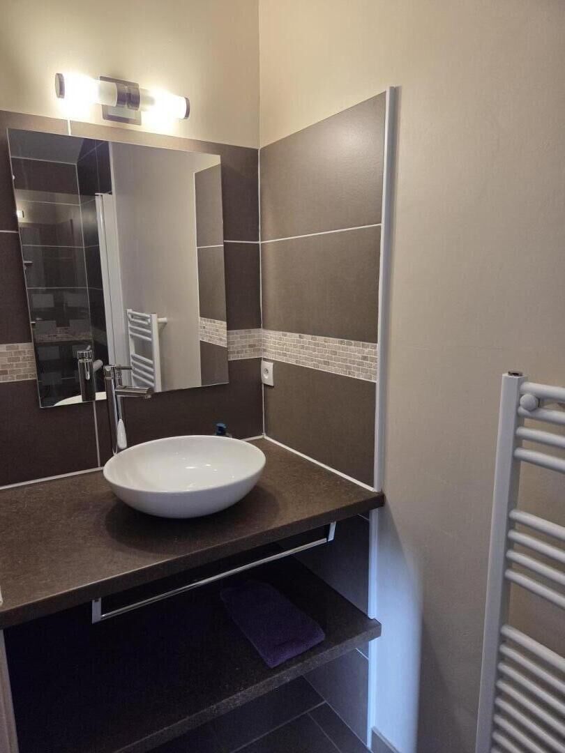 Une salle de bain avec un lavabo blanc, un miroir et un porte-serviettes.