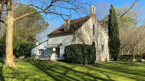 A stone building with a pitched roof, surrounded by a well-maintained lawn and trees.