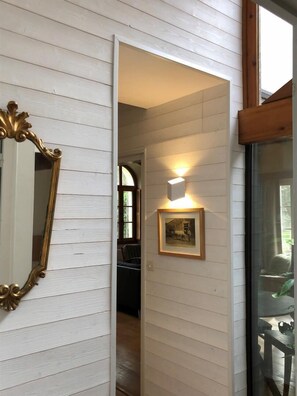 A hallway with white wooden walls, a framed mirror, a wall-mounted light, and a framed picture. - Gite DE Vacquey - Salleboeuf (SALLEBOEUF)