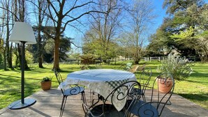 An outdoor dining area with a round table, chairs, and a lamp.