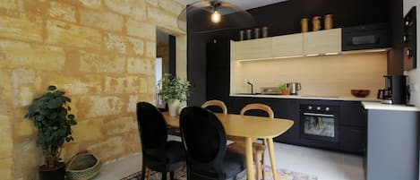 Een moderne keuken met zwarte kastjes, een houten eettafel en een hanglamp.