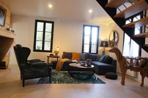 A living room with a sofa, armchair, coffee table, and a staircase. - La Borderie de Pomerol (POMEROL)