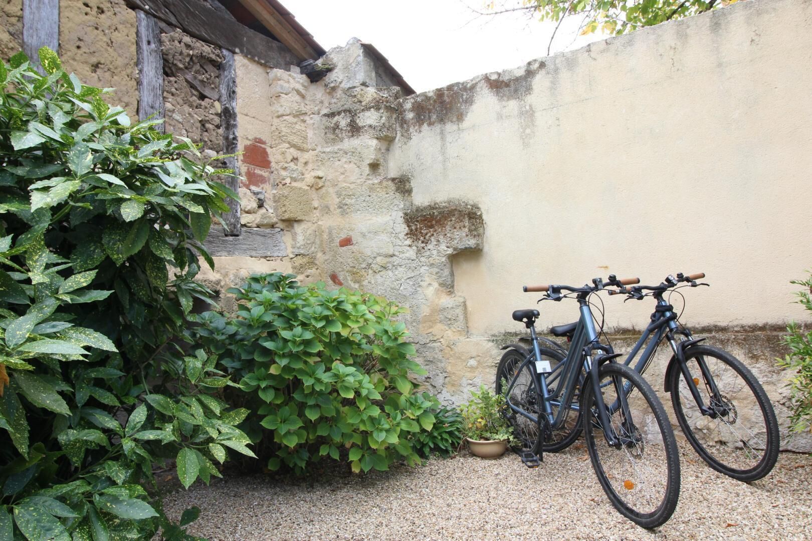 A bicycle parked against a wall in a courtyard with a gravel ground.