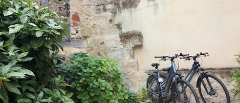 A bicycle parked against a wall in a courtyard with a gravel ground.