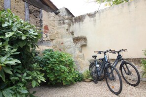 A bicycle parked against a wall in a courtyard with a gravel ground. - La Borderie de Pomerol (POMEROL)
