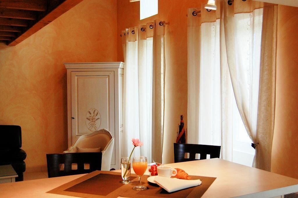 Un coin repas avec une table mise pour le petit-déjeuner, comprenant des croissants, un verre de jus d’orange et une tasse.