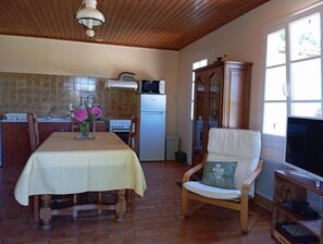 A kitchen with a dining table, chairs, a cabinet, and a television.