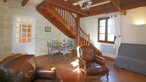 Una stanza con una scala in legno, un tavolo da pranzo con sedie, un divano e una finestra con tende.
