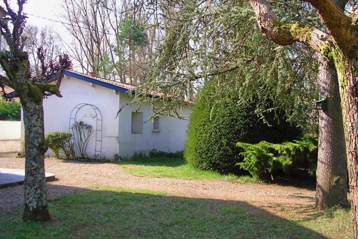 A white building with a blue roof, surrounded by trees and a well-maintained lawn.
