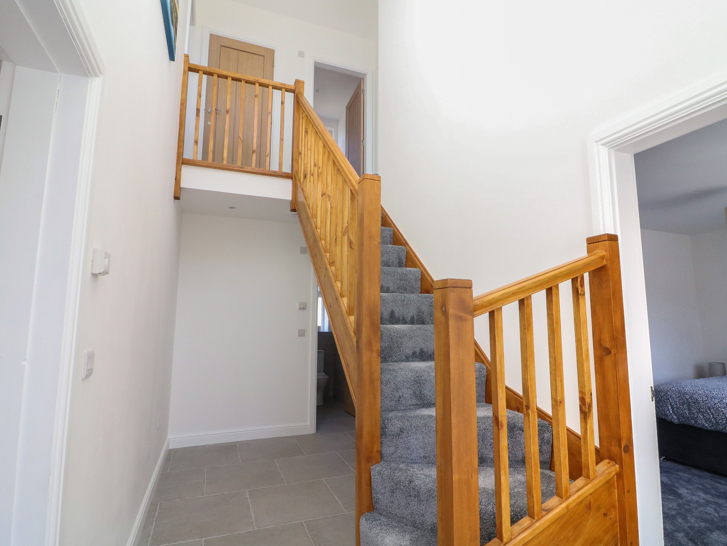 A staircase with wooden railings and carpeted steps leading to an upper floor.