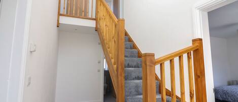 A staircase with wooden railings and carpeted steps leading to an upper floor.