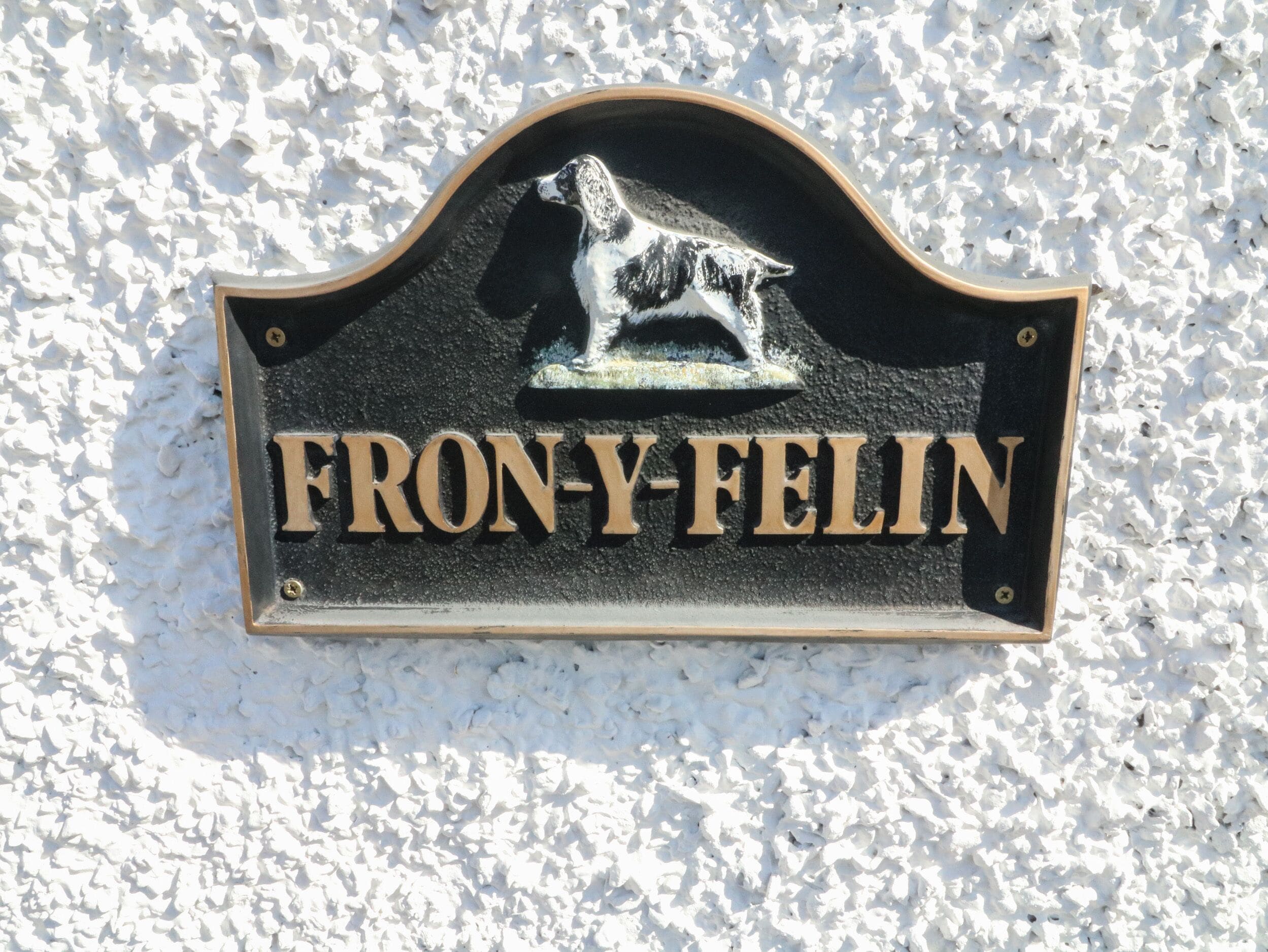 A black metal sign with the name "FRON-Y-FELIN" and a dog silhouette.
