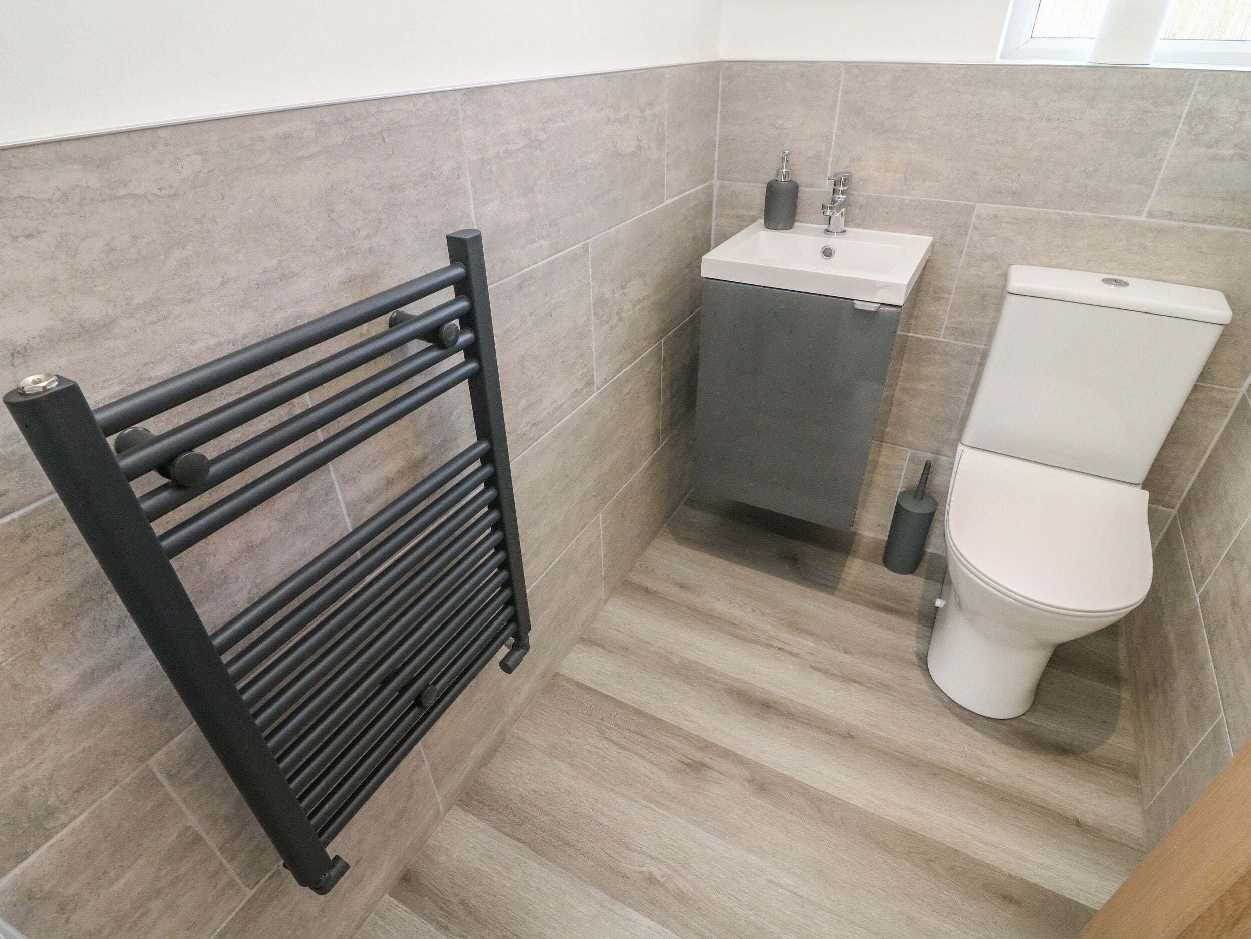 A bathroom with a black towel rack, a white sink, and a toilet.